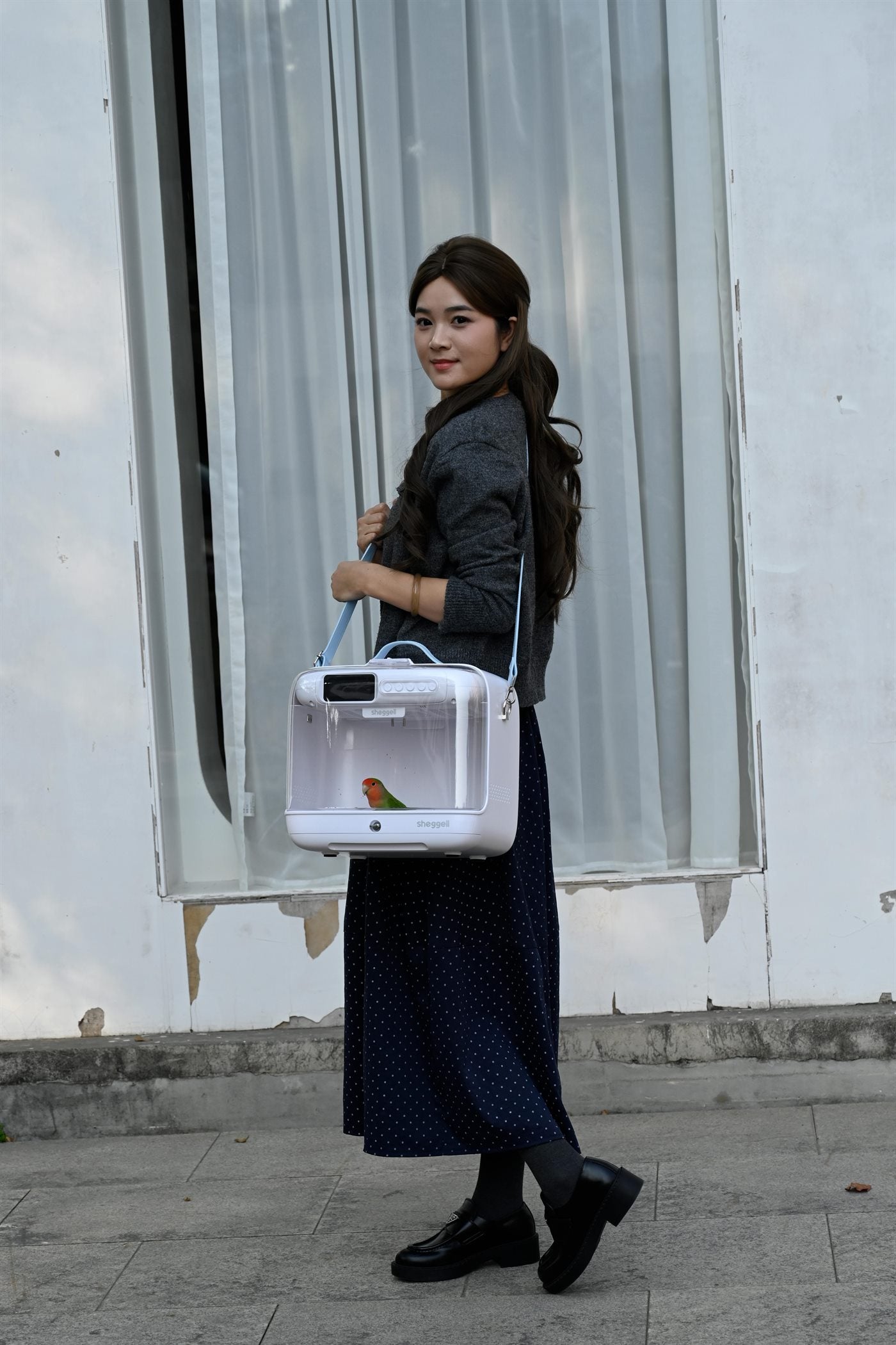 A bird keeper carrying the SHEGGELL enclosure with its shoulder strap